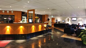 A hotel lobby with a reception desk, seating area, and a bar. - 2Home Stockholm South (Arsta)