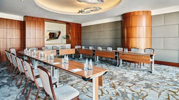 A conference room with long tables, chairs, and a modern chandelier.