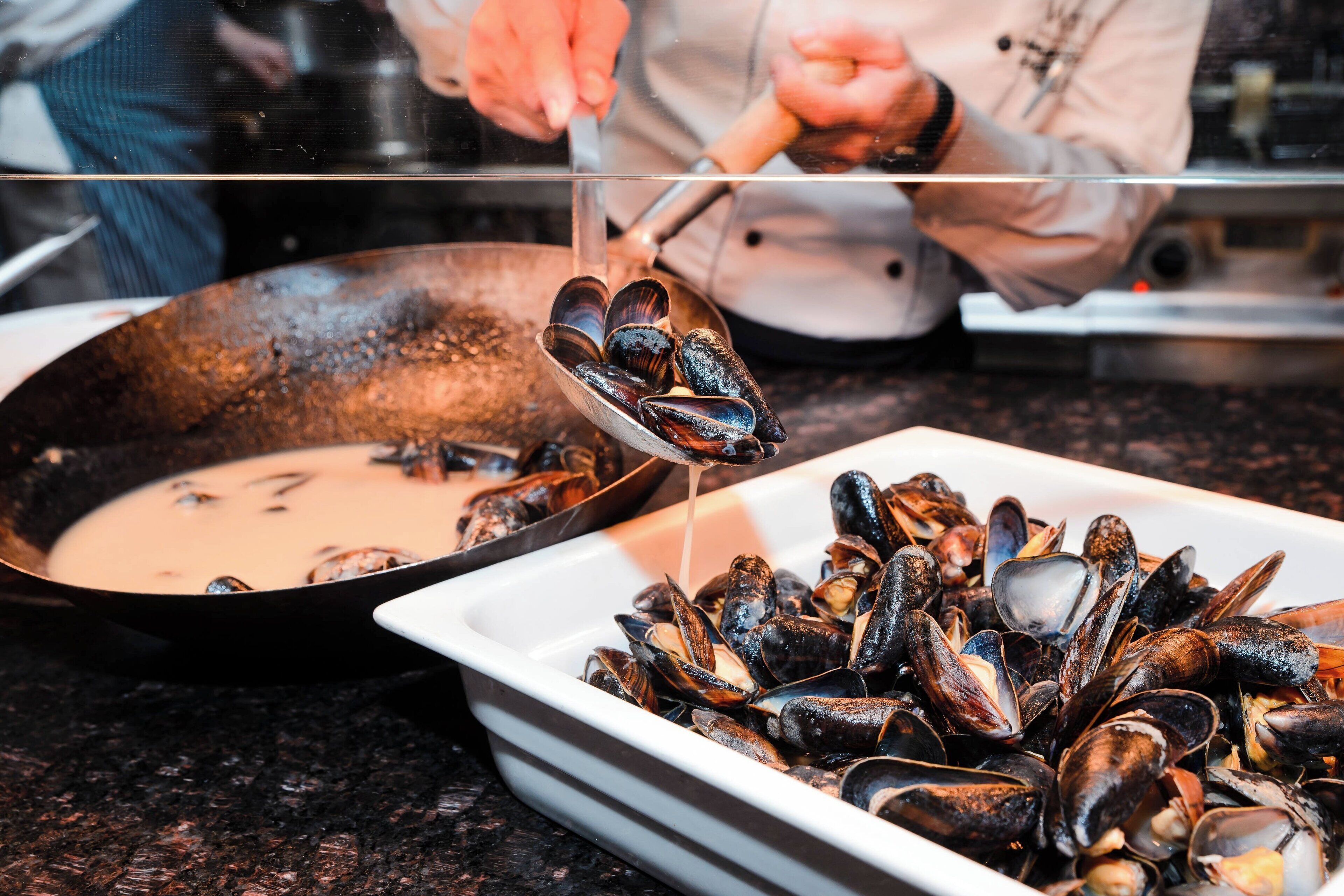 Uno chef cucina cozze in padella.