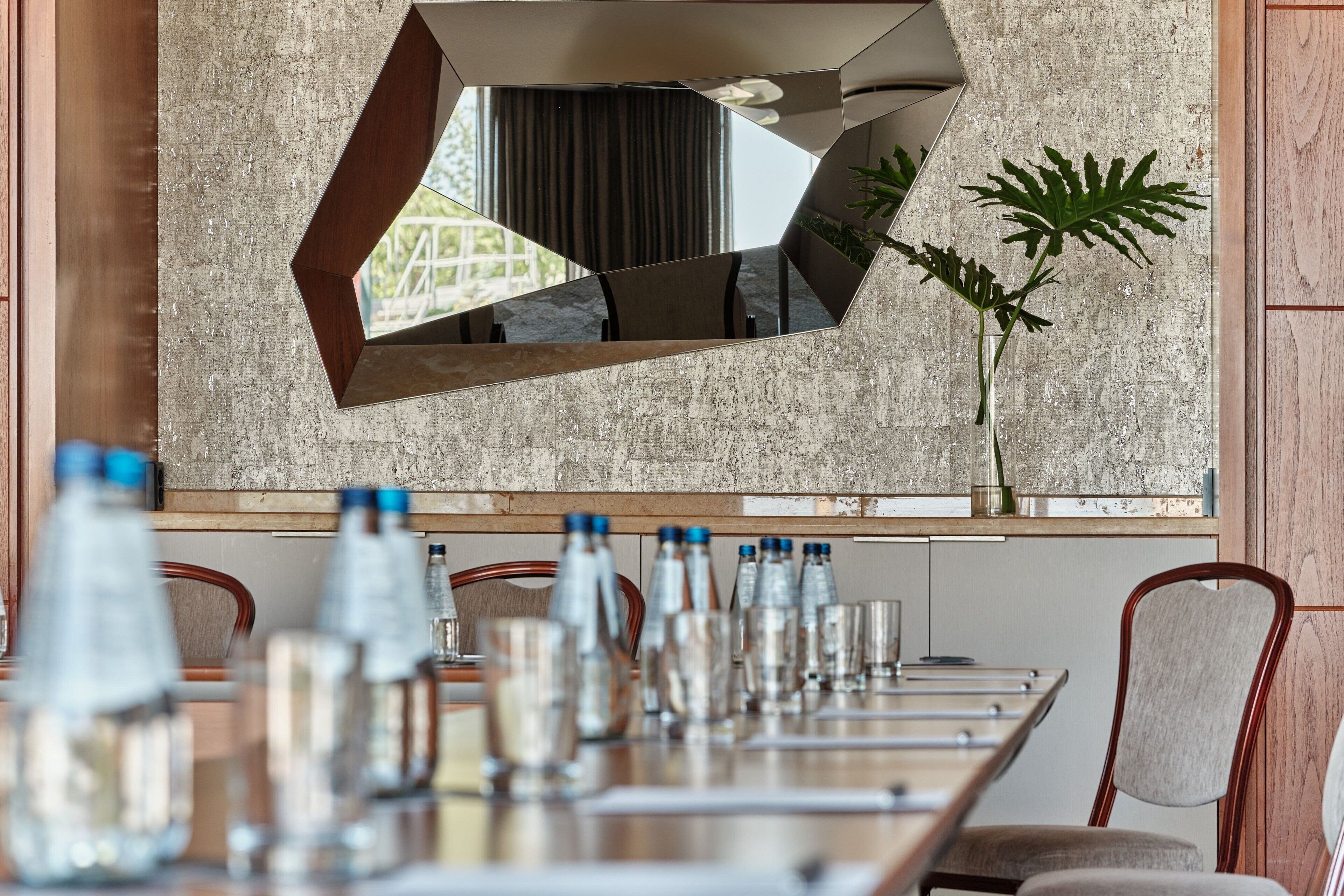 A conference room with a long table, chairs, and a large mirror on the wall.