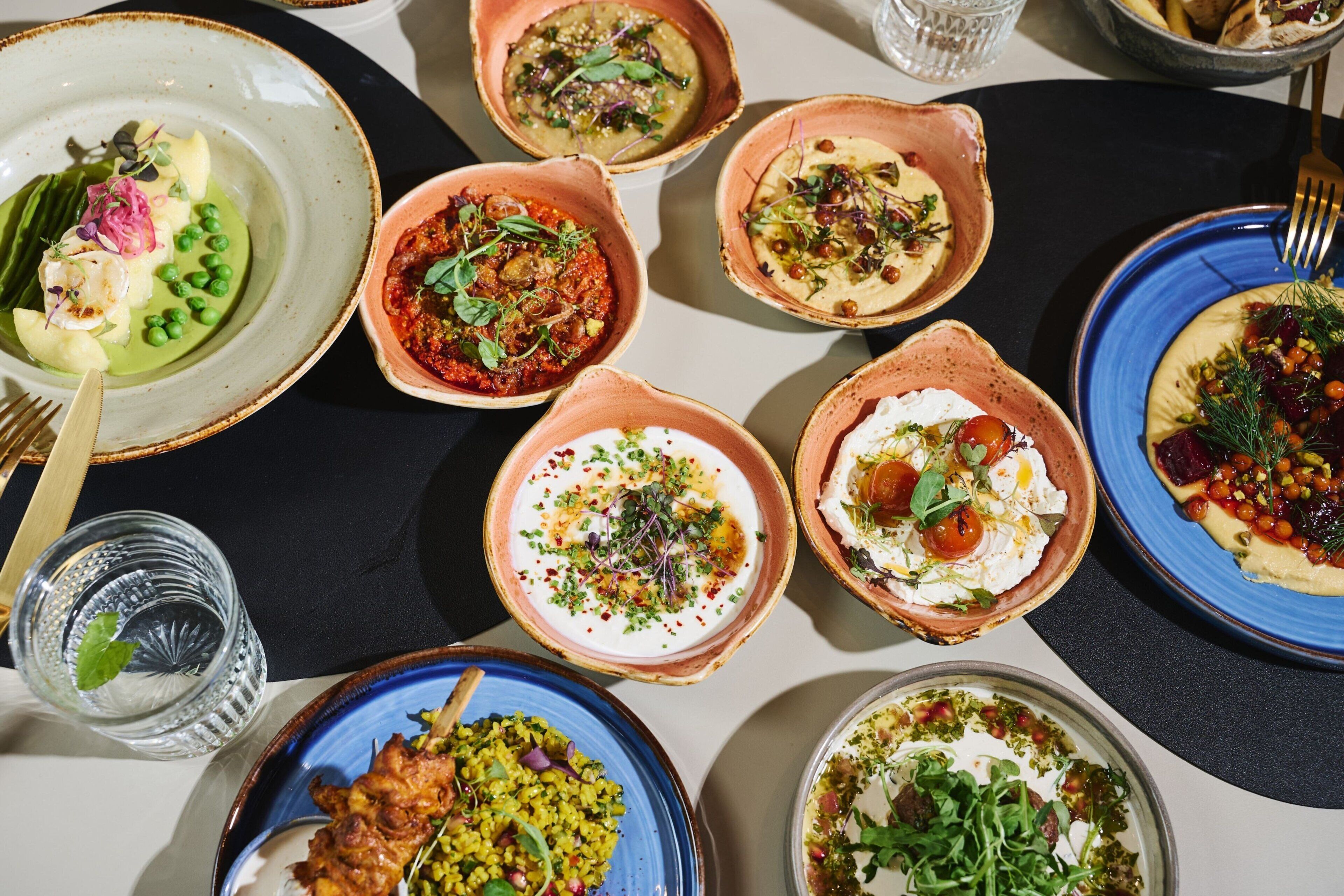 A variety of dishes on a table, including bowls of soup, salads, and other appetizers.