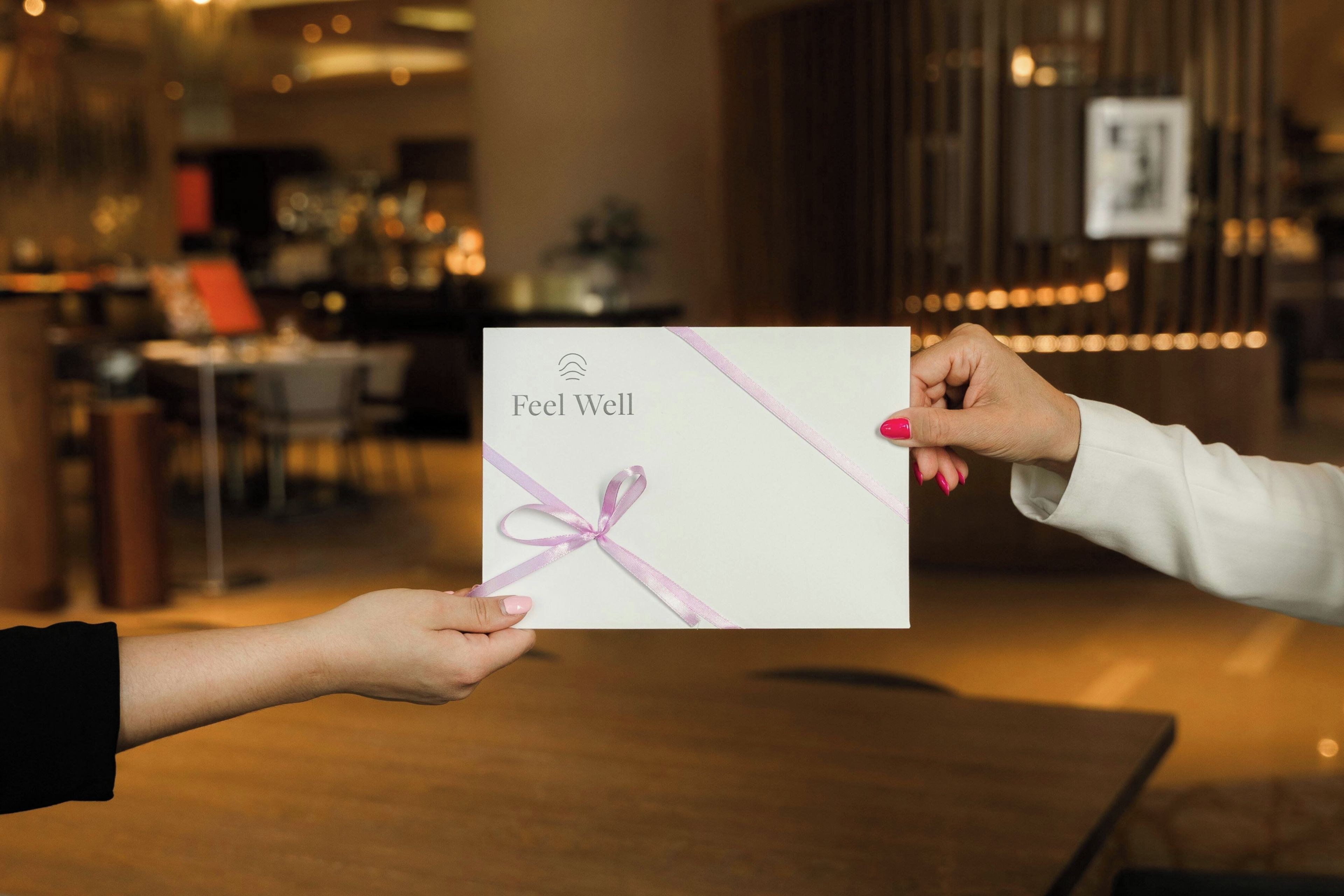 Una persona sosteniendo una tarjeta con el texto 'Feel Well' y un lazo.