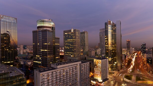 A cityscape with modern high-rise buildings, a prominent billboard, and a busy intersection with light trails from moving vehicles. - The Westin Warsaw (Warsaw)