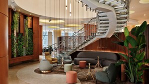 A modern lobby with a curved staircase, plush seating, and vertical gardens. - The Westin Warsaw (Warsaw)