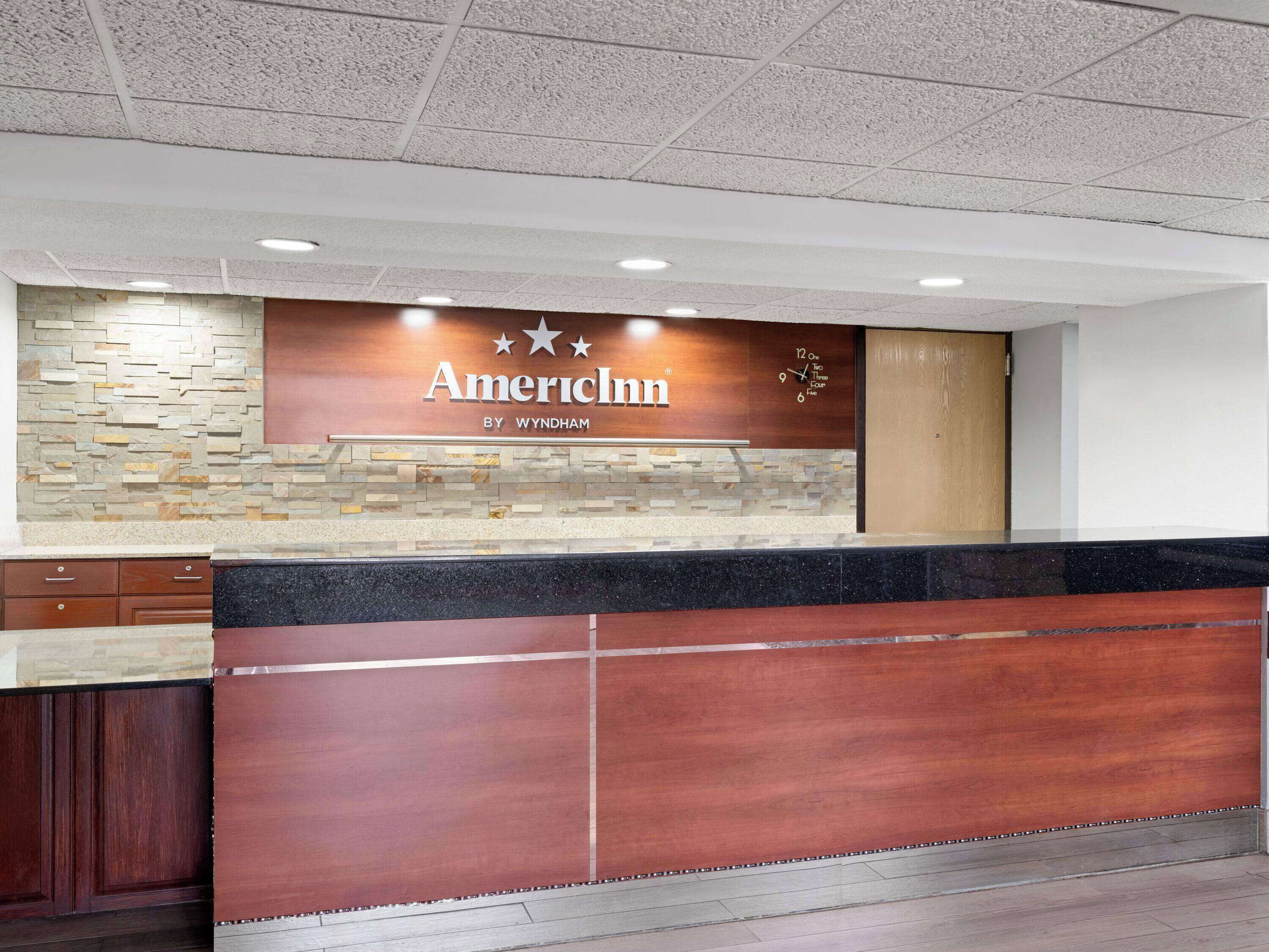 A reception desk with a stone wall and a clock.