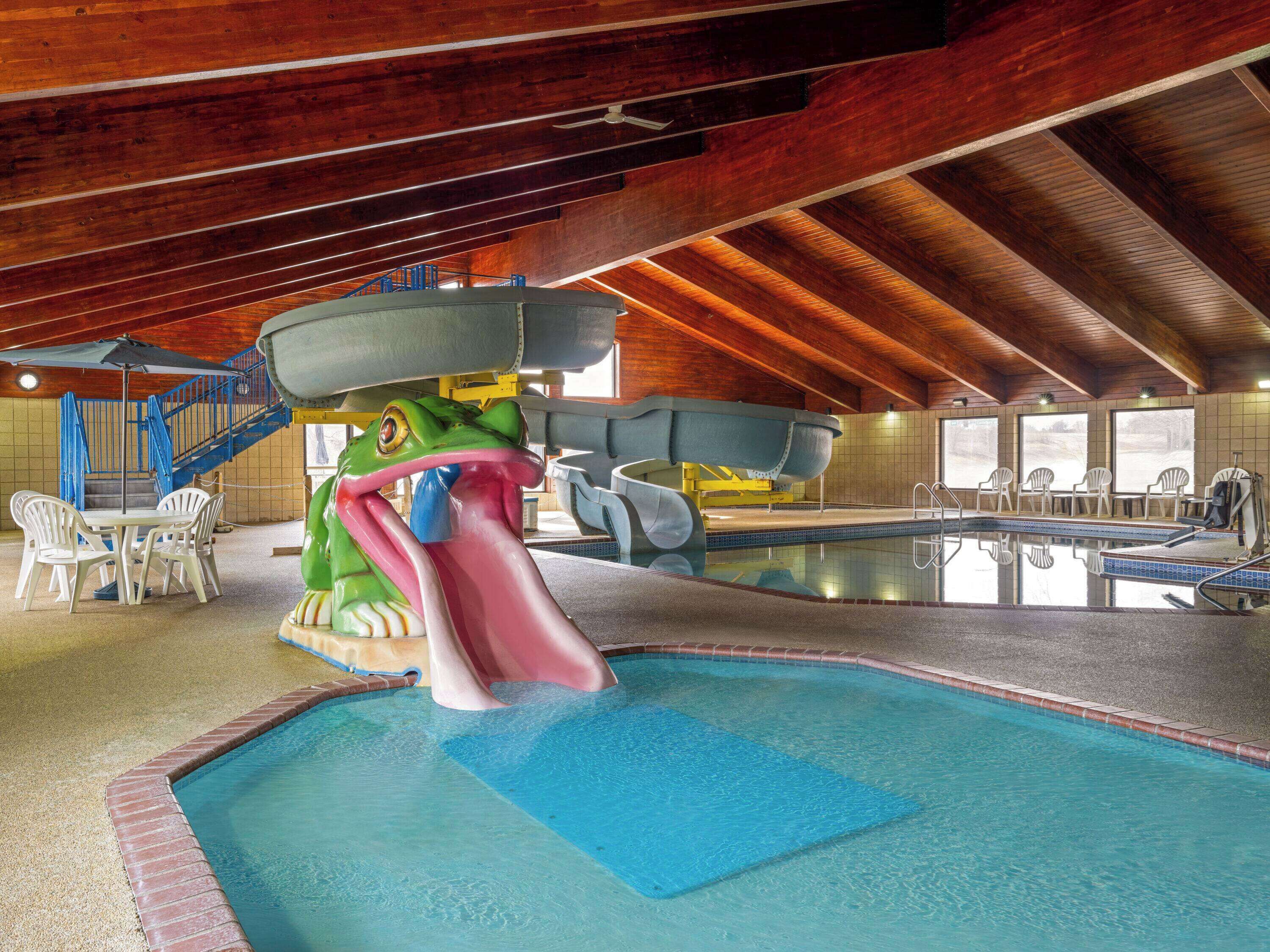 Una piscina interior con tobogán, zona de estar y escalera.