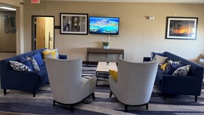 Un hall d’entrée avec deux canapés, une table basse et un téléviseur fixé au mur.