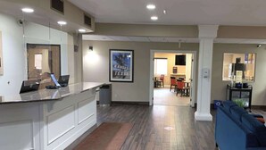 Une cuisine moderne dotée d’un îlot central, un coin repas avec une table et des chaises, et un salon avec un canapé bleu.