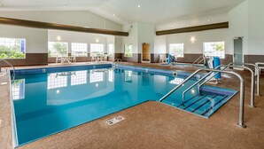 An indoor swimming pool with clear blue water, surrounded by seating areas and windows. - Comfort Inn Story City (Story City)