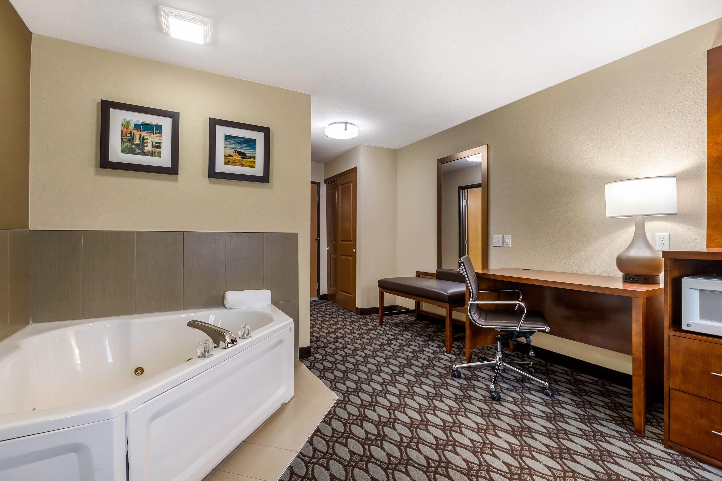 A hotel bathroom with a bathtub, a sink, a mirror, and a chair.