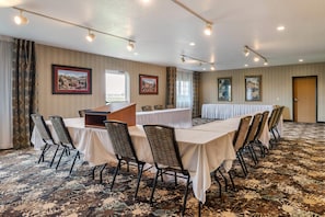 Une salle de conférence avec une longue table, des chaises et un pupitre.