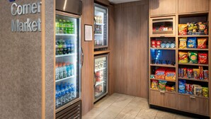 Una tienda de barrio con dispensadores refrigerados para bebidas y estantes con productos de snack.