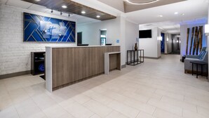 A modern reception area with a wooden reception desk, a large abstract blue and white wall art, and a minimalist design.