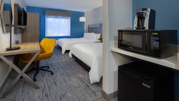Habitación de hotel con dos camas, un escritorio con silla, un microondas y un refrigerador.