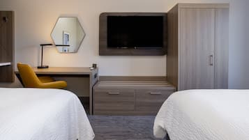 A hotel room with two beds, a desk, a chair, a television, and a wardrobe.