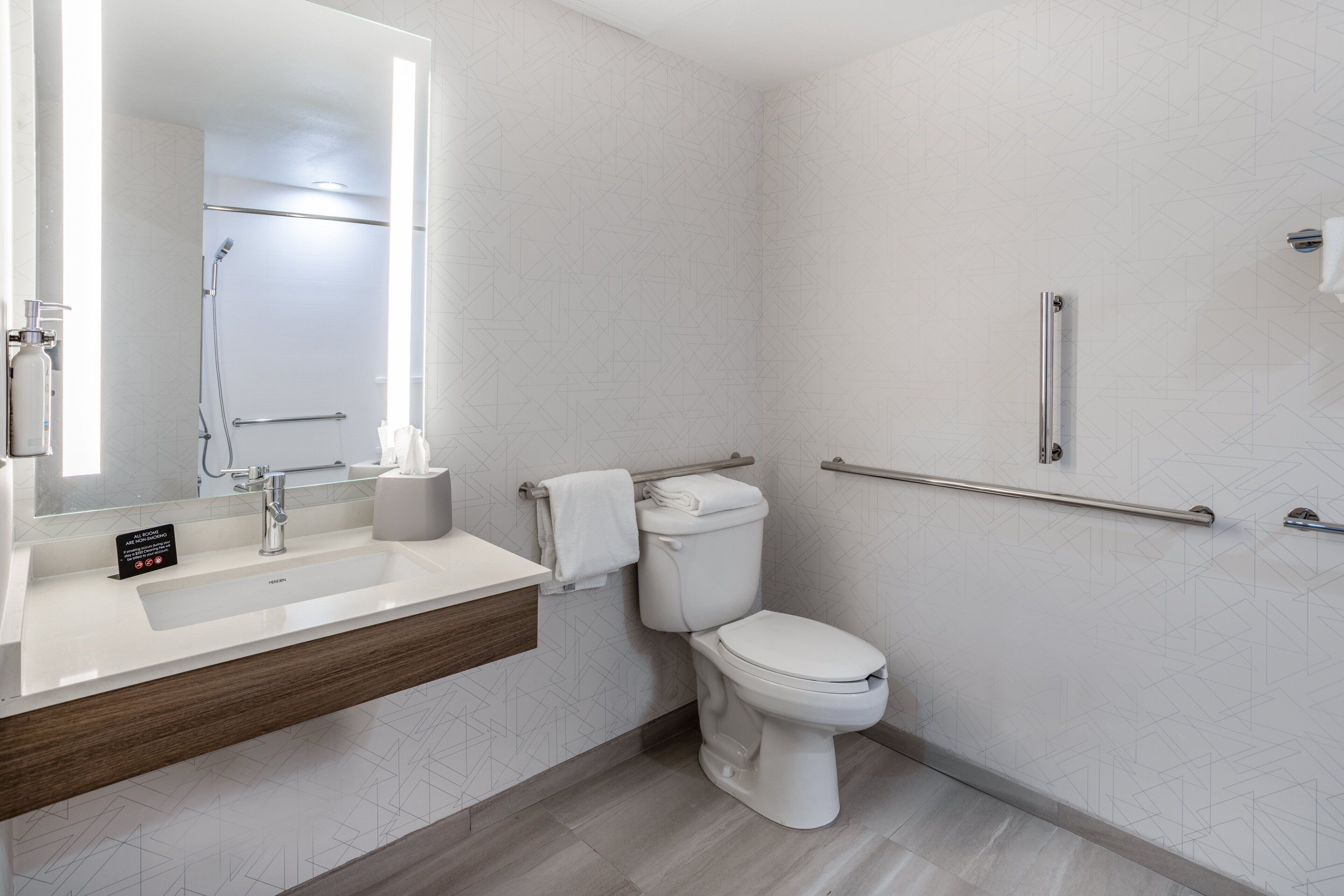 Et moderne badeværelse med hvid vask, spejl og toilet.