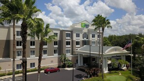 A hotel with a modern facade, multiple balconies, and a well-maintained lawn.