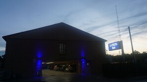 A brick building with a sign for 'La Villita Inn' and a parking area with cars. - La Villita Inn (San Antonio)