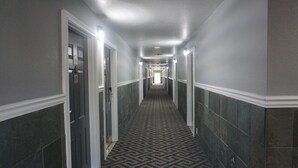 A long, narrow hallway with a patterned carpet and tiled walls. - La Villita Inn (San Antonio)