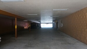 A long, narrow hallway with a high ceiling, concrete floor, and brick walls. - La Villita Inn (San Antonio)