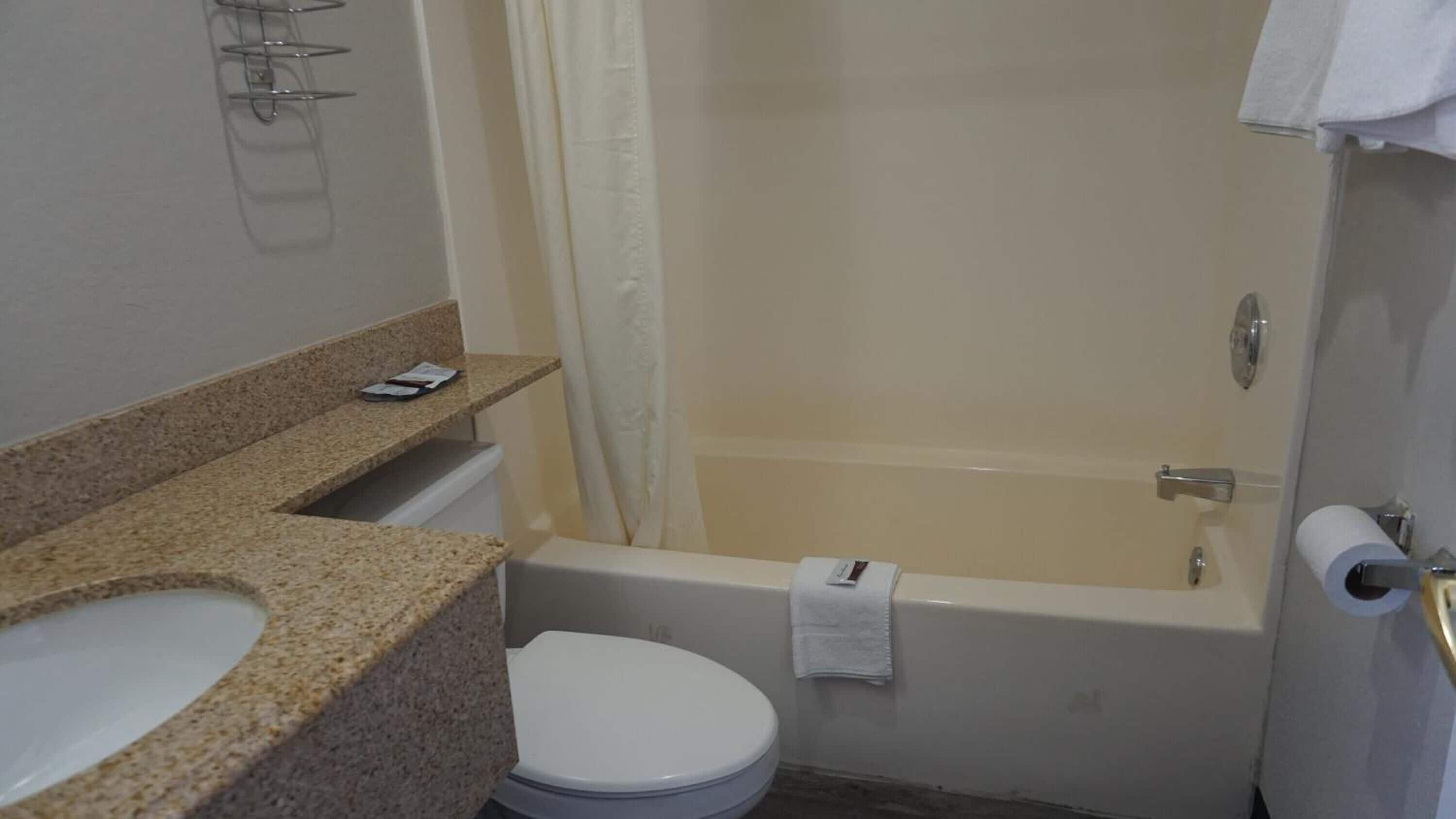 Un baño con lavamanos, inodoro, bañera y cortina de ducha.
