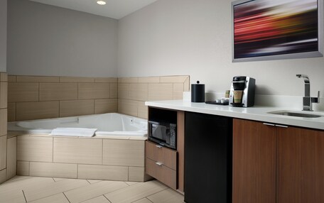 A modern bathroom with a built-in bathtub, a sink, a coffee machine, and a microwave.