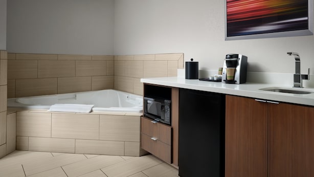 Un baño moderno con bañera integrada, lavabo, cafetera y microondas.