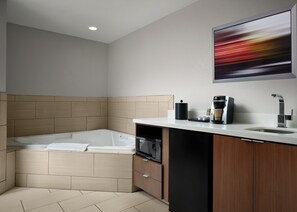 Une salle de bain moderne équipée d’une baignoire intégrée, d’un lavabo, d’une machine à café et d’un four à micro-ondes.