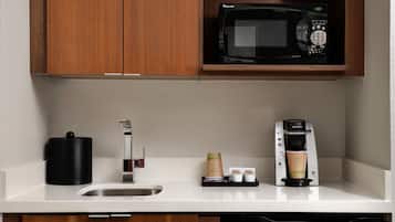 A kitchen with a microwave, coffee maker, and a sink.