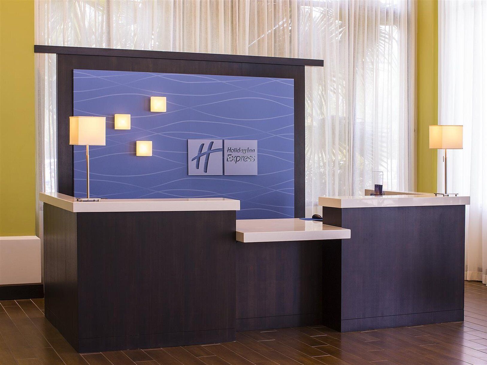 A reception desk with a blue patterned backdrop, a logo, and two lamps.
