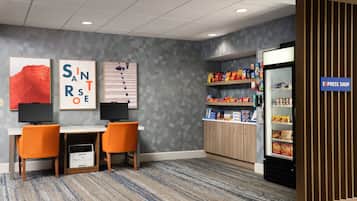 Een hotelkamer met een bureau, twee stoelen, een televisie, een minibar en een snackgedeelte.