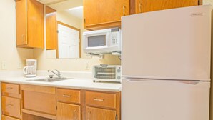 Eine Küche mit Holzausstattung, einem weißen Kühlschrank, einer Mikrowelle, einer Kaffeemaschine und einem Toaster.