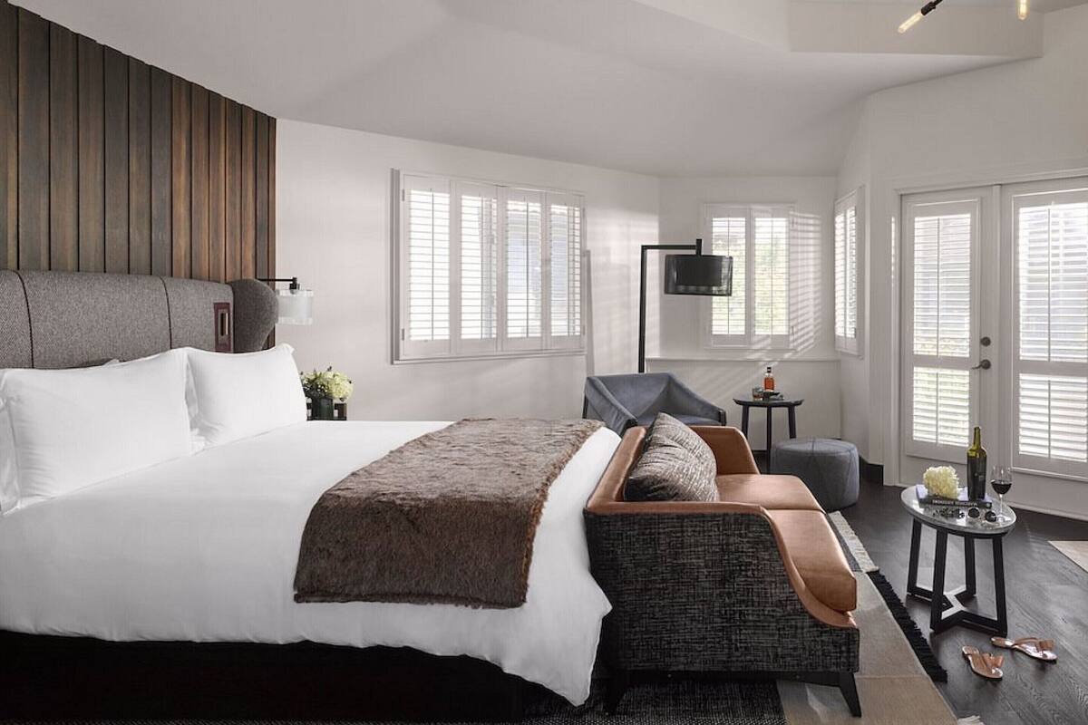 A modern bedroom with a large bed, a sofa, a TV, and a small table.