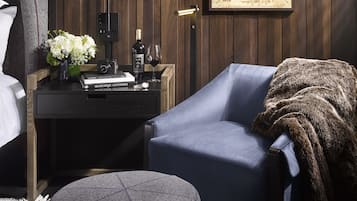 A room with a bed, a desk with a map, a chair, and a round ottoman.