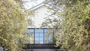 A modern house with a glass entrance, a white exterior, and a garden area with trees and plants. - The Estate Yountville (Yountville)