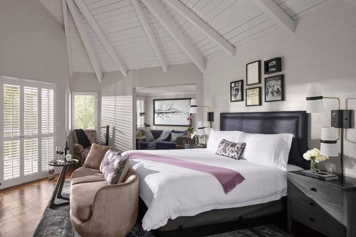 A bedroom with a large bed, a ceiling fan, and a view of the outdoors through the windows.