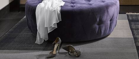 A modern bedroom with a built-in wardrobe, a purple ottoman, and a coffee table.