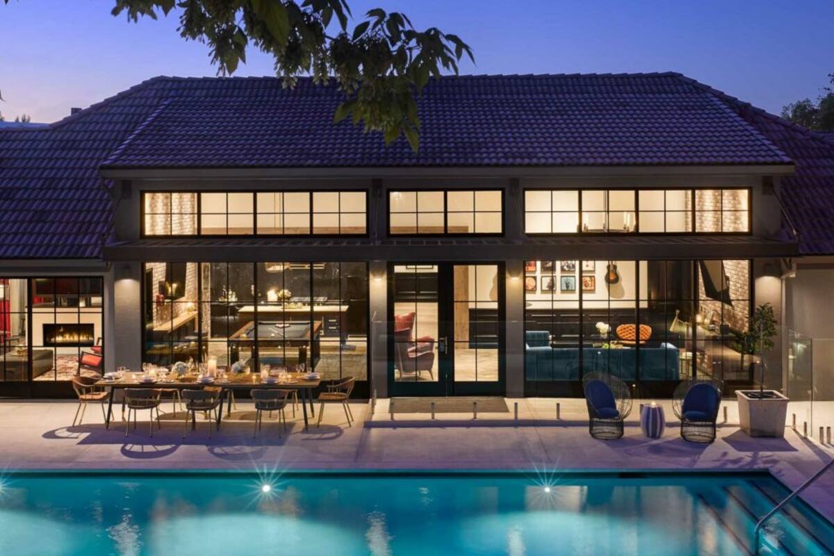 A modern house with a swimming pool, large windows, and a dining area.