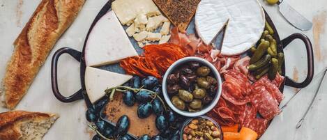 A charcuterie board with various cheeses, meats, grapes, olives, and pickles.