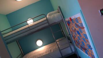 A bunk bed room with a ceiling light, a window, and a colorful wall decoration.