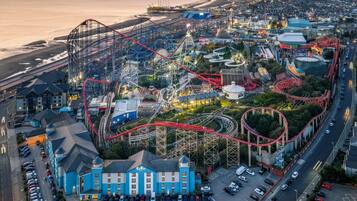 Ein Küsten-Freizeitpark mit Achterbahnen, einem Hotel und einem Parkplatz.