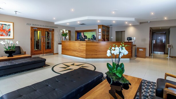 Un hall de hotel con mostrador de recepción, zona de estar y un cuadro abstracto grande en la pared.