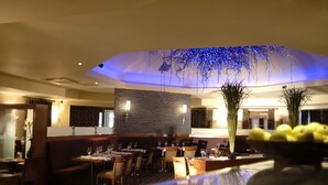 Un restaurante con techo alto, iluminación azul y una fuente central.
