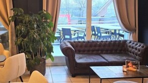 A cozy lounge area with a sofa, chairs, a coffee table, and a large potted plant.