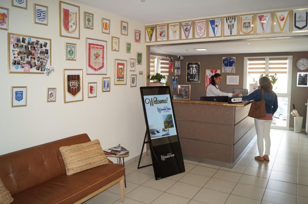 Zona de recepción de un hotel con premios enmarcados en las paredes, un mostrador de recepción y un cartel.