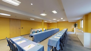 A conference room with multiple tables, chairs, and a long table with a blue tablecloth. - Hotel Stand'Inn (Mondercange)