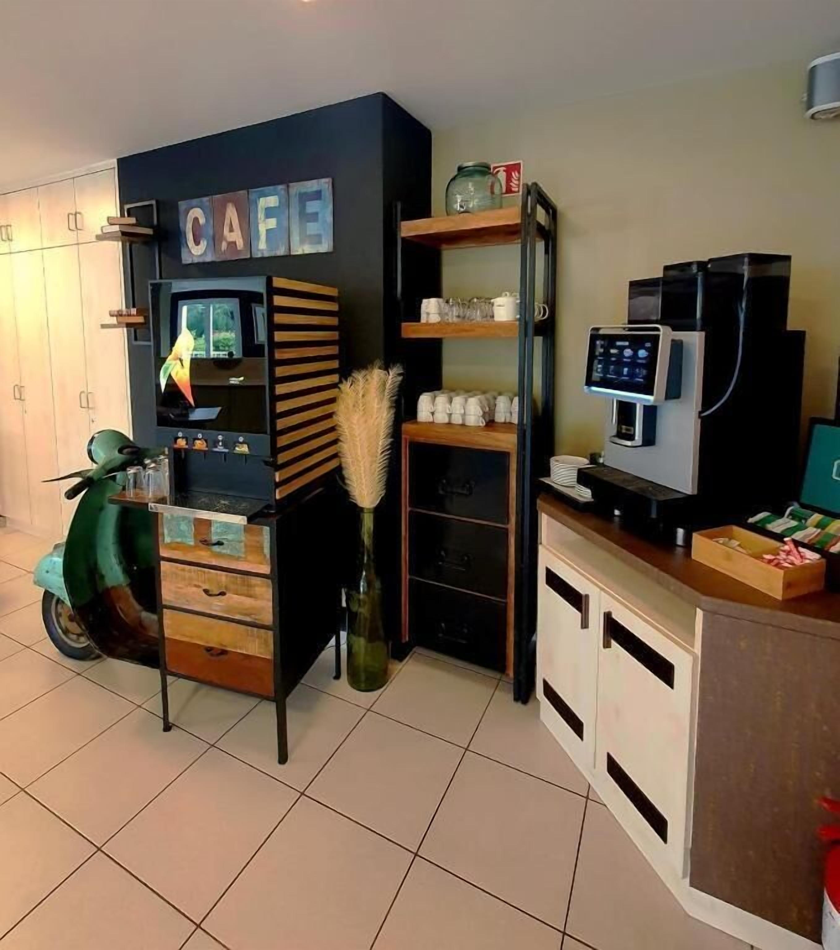 A compact living space with a kitchenette, a coffee machine, and a television.
