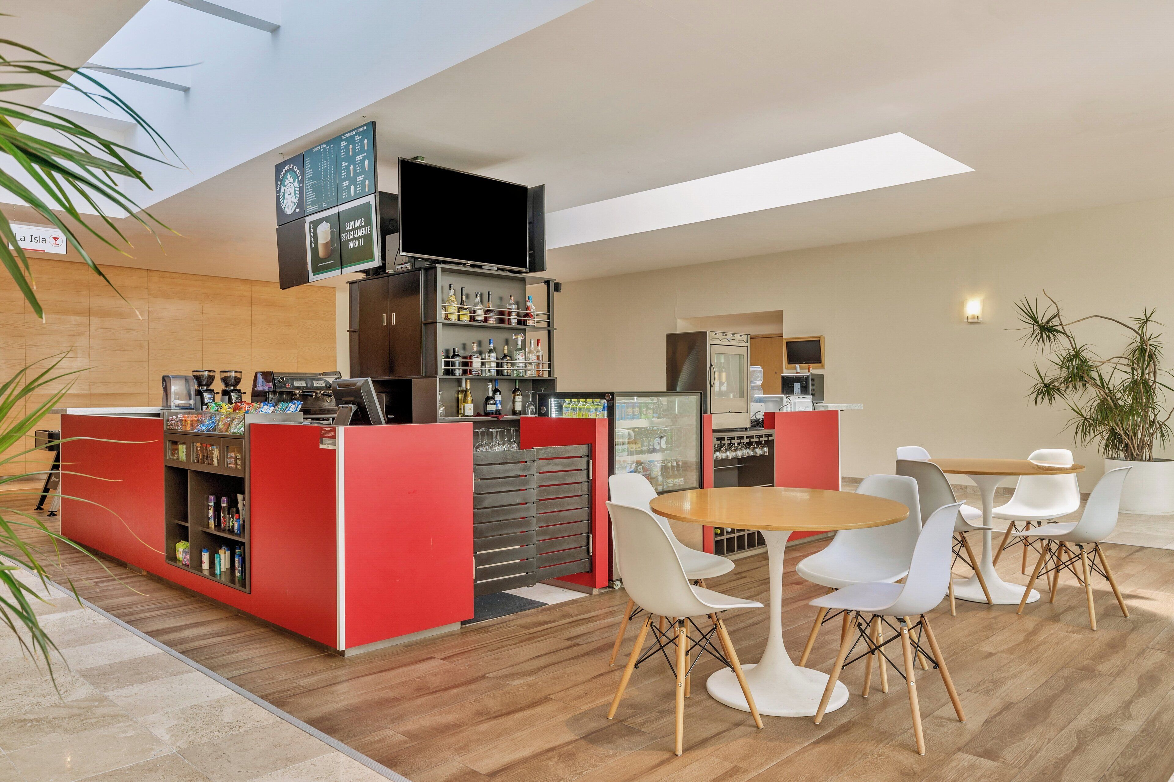 Een modern café met een rode toonbank, witte stoelen en een houten tafel.