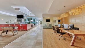 Un espacio de oficina moderno con una larga mesa de madera, varias sillas y múltiples monitores de ordenador.