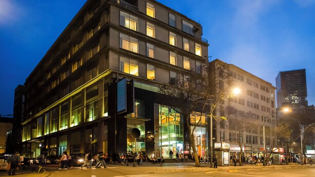 Un hotel de varios pisos con una fachada moderna, ventanas amplias y entrada a nivel de calle.